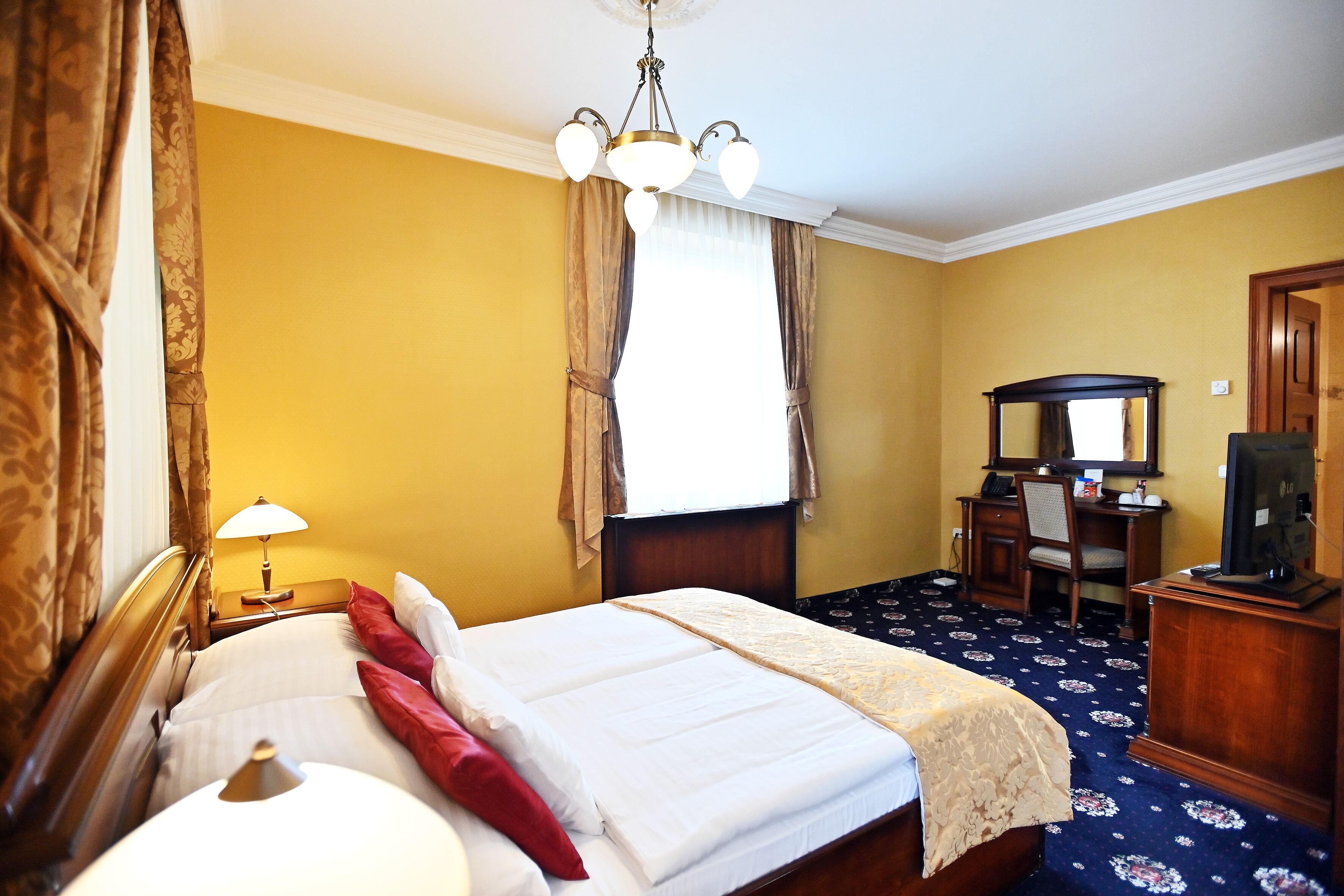Une chambre d’hôtel équipée d’un lit, d’un bureau, d’une chaise, d’une télévision et d’une lampe.