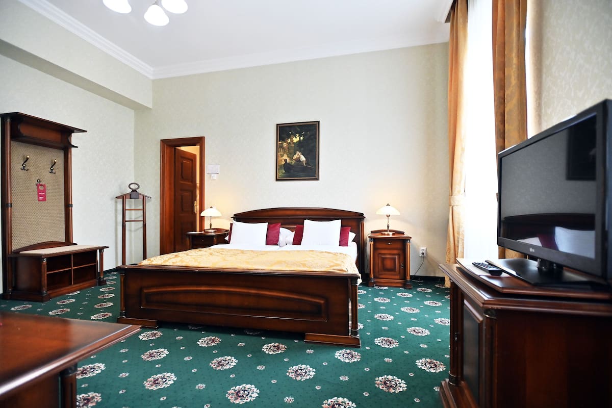 A hotel room with a large bed, a television, a desk, and a wardrobe.