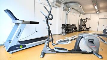 Un gimnasio con equipo cardiovascular, incluyendo cintas de correr y una máquina elíptica.
