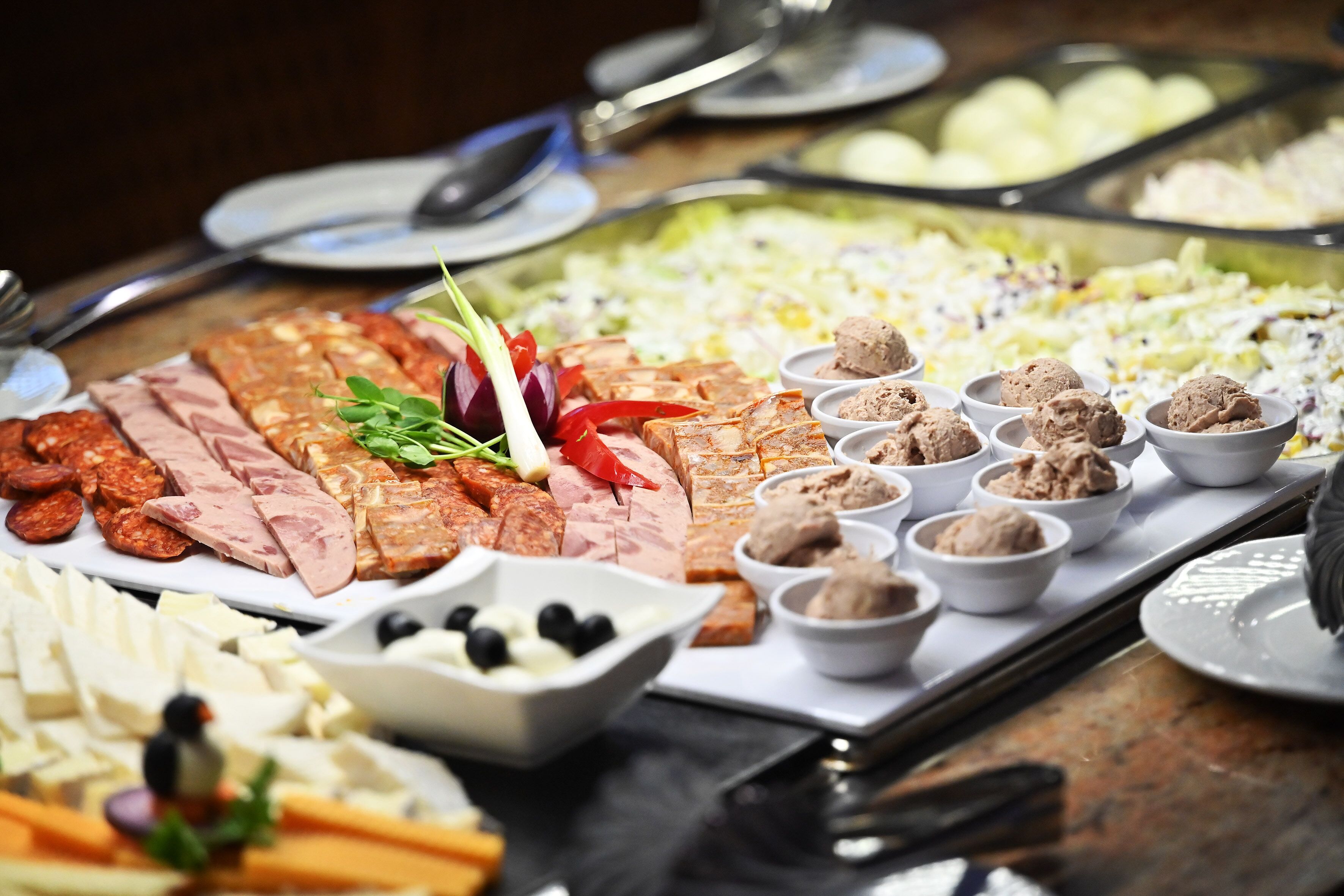 Un bufé con diversas opciones de comida, incluyendo carnes, quesos y salsas.