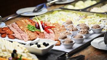 Un bufé con diversas opciones de comida, incluyendo carnes, quesos y salsas.
