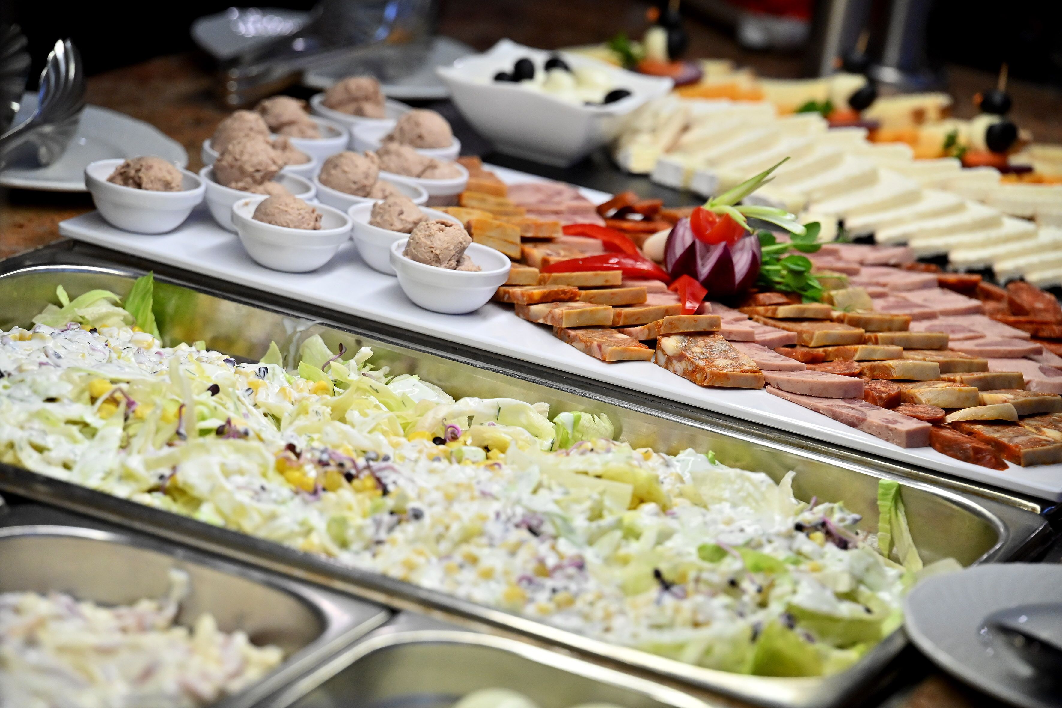 Un buffet proposant une variété de plats, notamment des salades, des viandes et des sauces.