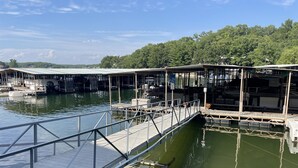A marina with docked boats, a wooden walkway, and a covered area with a flag.