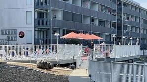 A multi-story hotel with balconies, outdoor seating, and American flags.