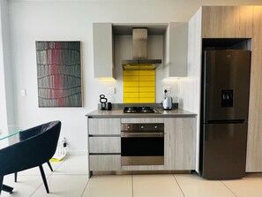 Uma cozinha moderna com fogão embutido, forno e geladeira de aço inoxidável.