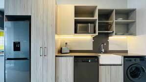 A modern kitchen with a built-in dishwasher, microwave, and washing machine. - Modern 1 Bed Apartment in Trendy Rosebank (Johannesburg)