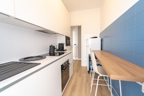 A modern kitchen with a built-in oven, a coffee maker, and a wooden table with bar stools. - Le Orchidee by Wonderful Italy (Sanremo)