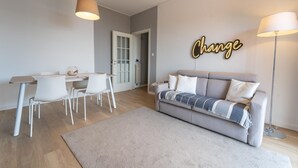 A modern living room with a sofa, dining table, chairs, and a 'Change' sign on the wall. - Le Orchidee by Wonderful Italy (Sanremo)