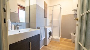A modern bathroom with a large mirror, a washing machine, a shower, and a toilet. - Le Orchidee by Wonderful Italy (Sanremo)