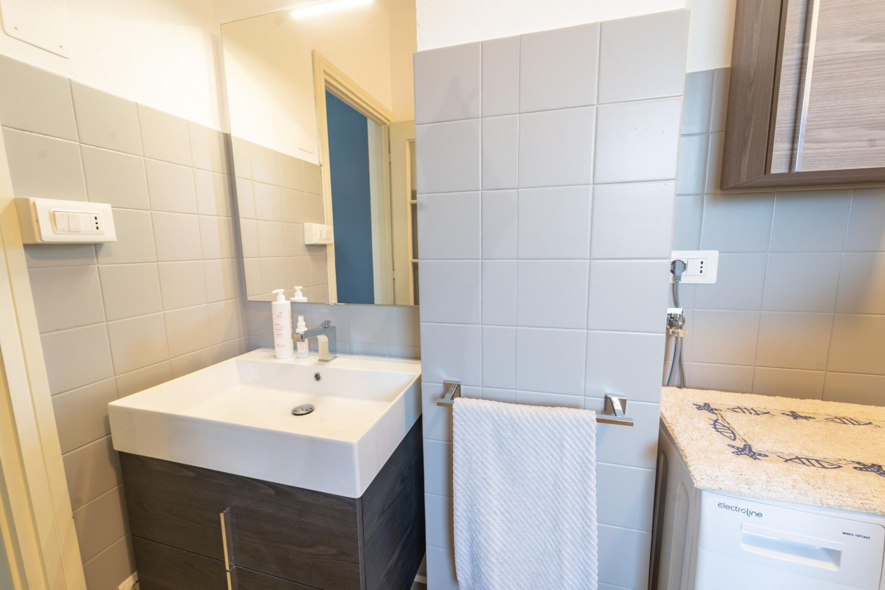 Une salle de bain avec un lavabo blanc, un meuble en bois foncé et un porte-serviettes.