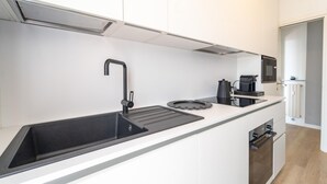 A modern kitchen with a black sink, white cabinets, and a built-in oven. - Le Orchidee by Wonderful Italy (Sanremo)