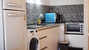 A compact kitchen with a washing machine, a microwave, and a toaster oven. - Excelente Ubicación (Ushuaia)