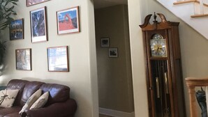 A spacious living room with a brown leather couch, a wooden staircase, and a wall adorned with framed pictures. - Privacy yet close to downtown Saratoga (Greenfield Center)