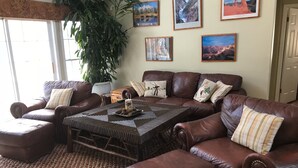 A living room with a brown leather sofa set, a coffee table, and a large potted plant. - Privacy yet close to downtown Saratoga (Greenfield Center)