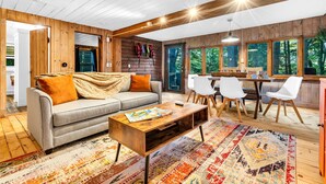 A cozy cabin interior with a sofa, coffee table, and dining area. - Pine and Eagle- Family & Dog Friendly Great Views (Sebago)
