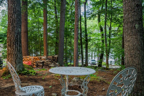 A round table with two chairs in a forest setting.