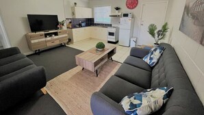 A modern living room with a grey sofa, a wooden coffee table, and a TV on a stand.