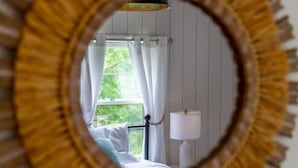 A bedroom with a bed, a nightstand, a lamp, and a window with curtains.