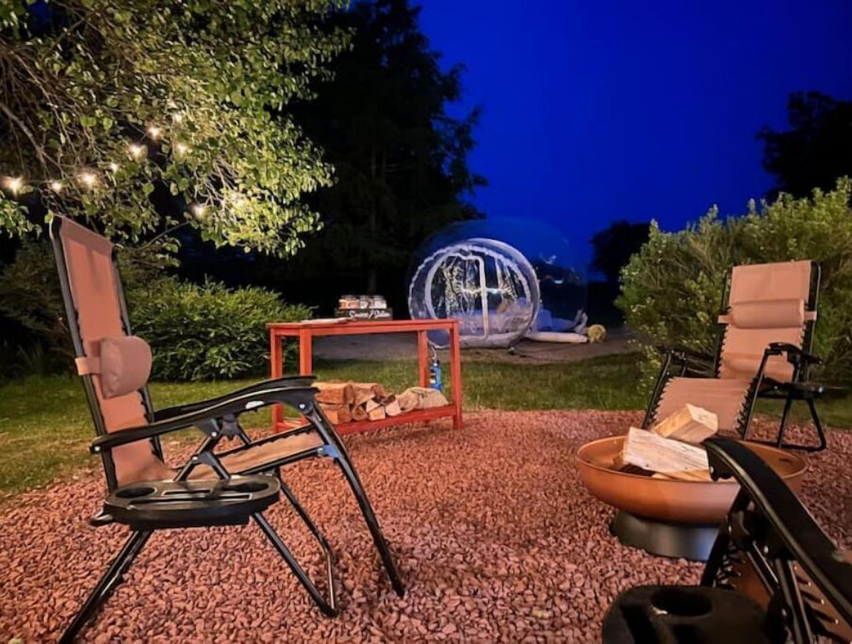 An outdoor seating area with two chairs and a table, surrounded by a gravel path and a decorative tree.