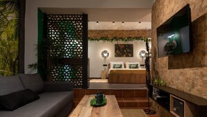 Una sala de estar moderna con un sofá, una mesa de centro y un televisor montado en una pared de piedra.