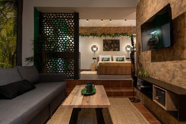 A modern living room with a sofa, coffee table, and a TV mounted on a stone wall.