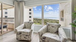 A balcony with two armchairs, a glass door, and a view of the beach. - Amelia Surf & Racquet Club Condo 5th Floor Oceanview Pools Tennis Court Sleeps 4 (Fernandina Beach)