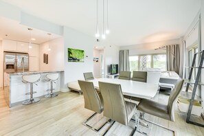 A modern kitchen with a built-in refrigerator, a dining area with a large table and chairs, and a seating area with a sofa and a TV. - Beachfront Vacation Rental w/ Hot Tub, Pool, Sauna (Miramar Beach)