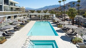 A pool area with lounge chairs and umbrellas, a bar, and a view of mountains.