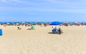 Uma praia com muitos guarda-sóis e cadeiras de praia coloridas, indicando um dia ensolarado.