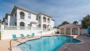 A pool area with a large pool, lounge chairs, and a building with balconies. - 2 King Beds - Walk to Beach (St. Augustine)