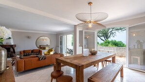 A spacious living area with a wooden dining table, a sofa, and a large mirror.
