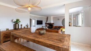 A spacious kitchen with a large wooden table, a hanging light fixture, and a modern fireplace.