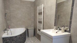 Ein modernes Badezimmer mit freistehender Badewanne, einem Waschtisch und einem Handtuchhalter.