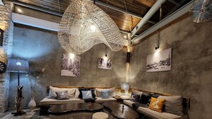 A cozy living room with a curved sofa, a large woven light fixture, and rustic decor. - Chalet Bromo lounge & lodge (Kedungredjo)
