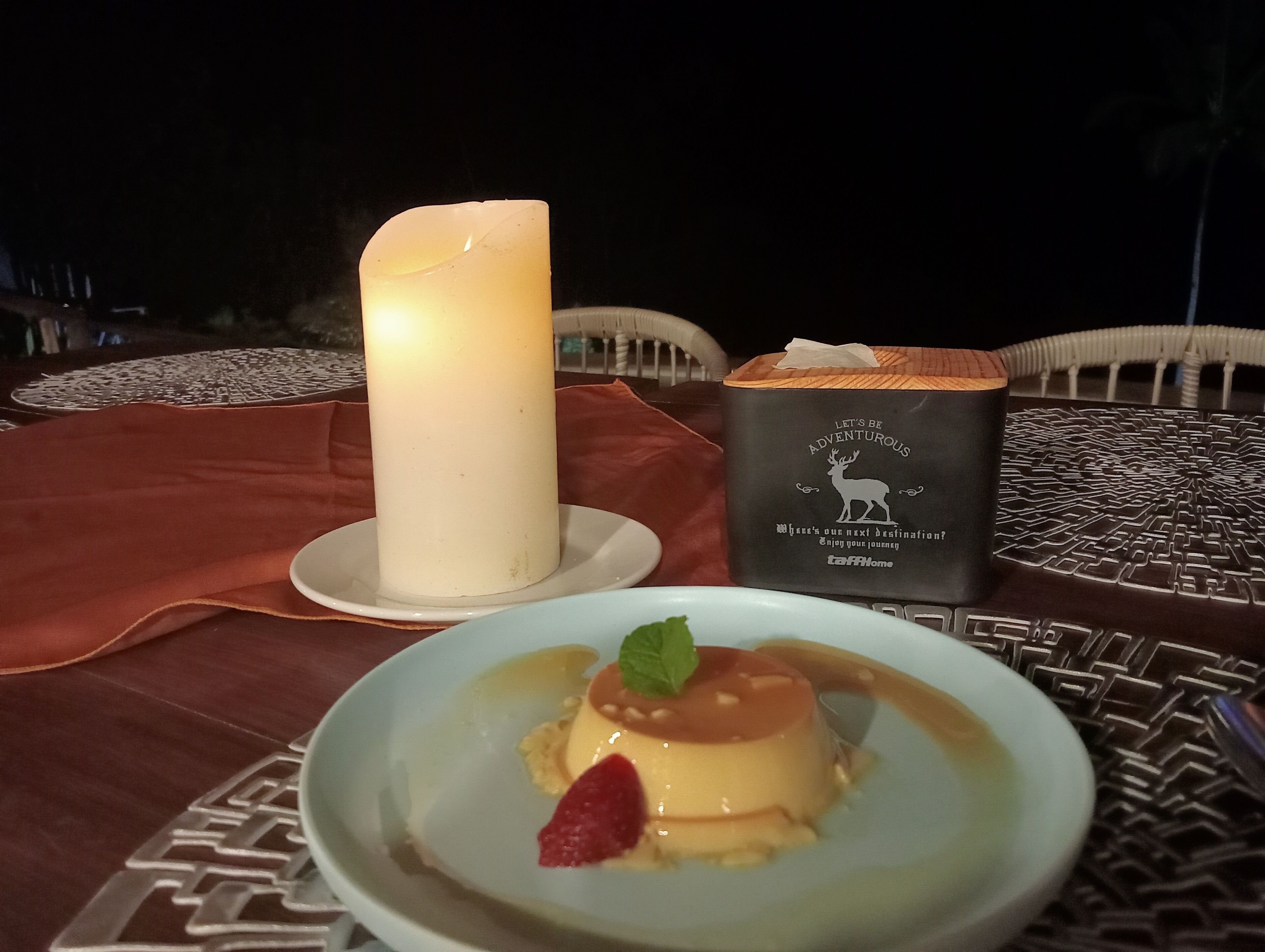 Una vela, una caja decorativa y un postre sobre una mesa.