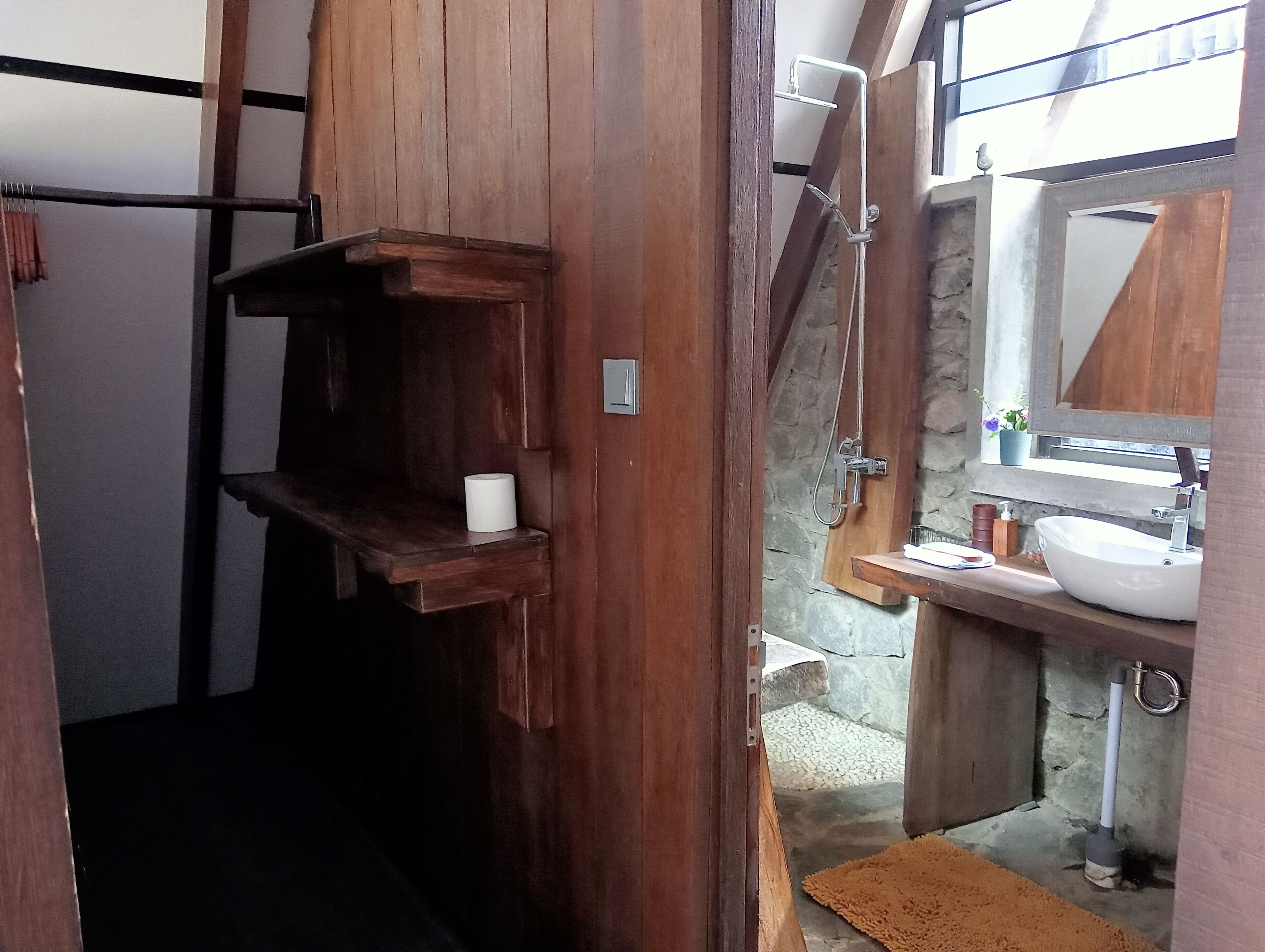 A bathroom with a wooden vanity, a sink, and a shower area.