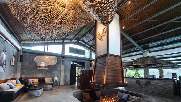 A spacious lounge area with a large fireplace, comfortable seating, and a high ceiling with natural light. - Chalet Bromo lounge & lodge (Kedungredjo)