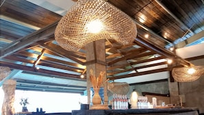 A modern interior with a high ceiling, exposed beams, and a central reception area with a woven light fixture. - Chalet Bromo lounge & lodge (Kedungredjo)