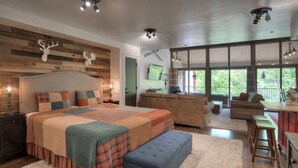 Un dormitorio amplio con una cama grande, un sofá y una zona de comedor con vistas.