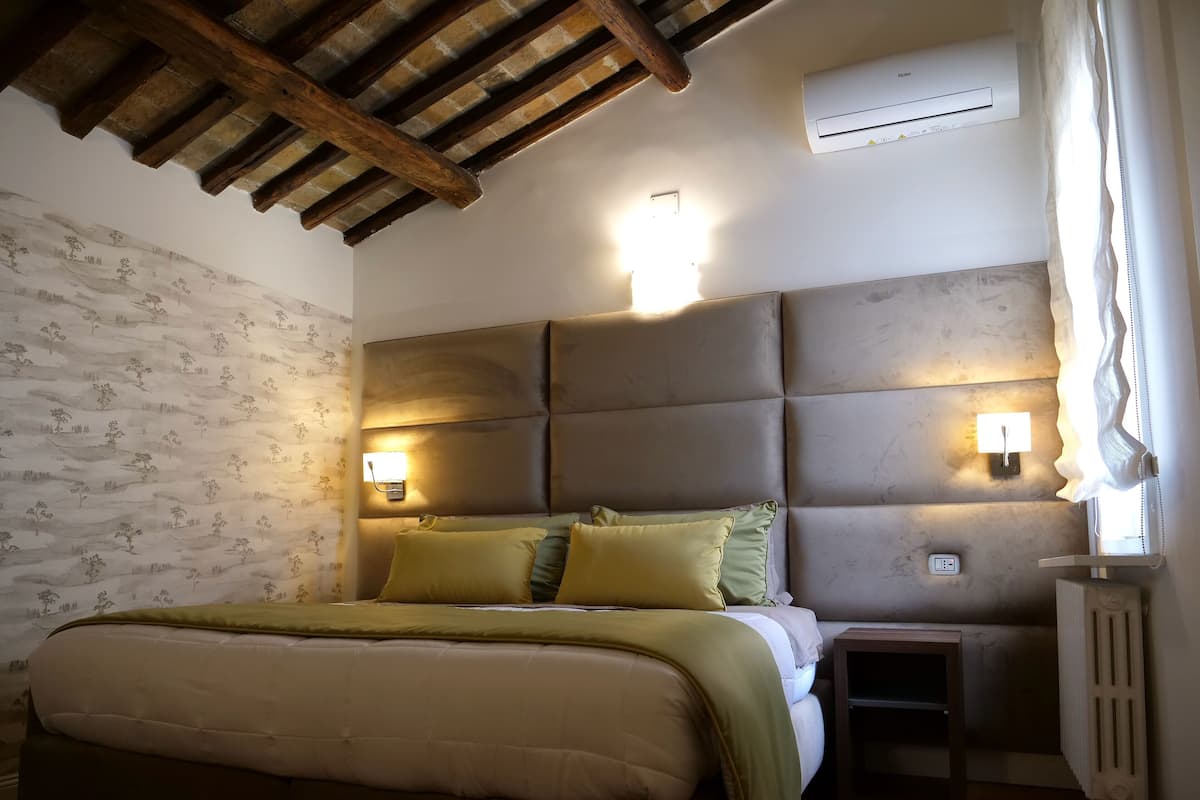 Ein Schlafzimmer mit Bett, Kopfteil, Nachttischlampen und einer Heizung.