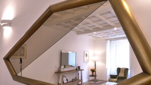 Een kamer met een grote spiegel, een bureau, een stoel, een lamp en een raam met gordijnen.