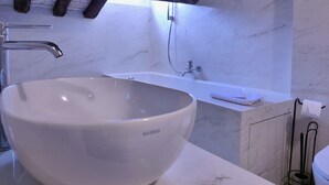 Een moderne badkamer met een ruime witte wasbak, een vrijstaand bad en een wand betegeld met marmer.