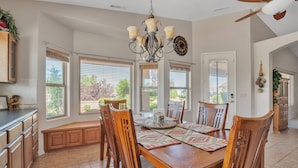 A spacious dining area with a wooden table, chairs, and a chandelier. - Hole in One! Luxury Home Near Golf Course, Airport, Embry Riddle (Prescott)