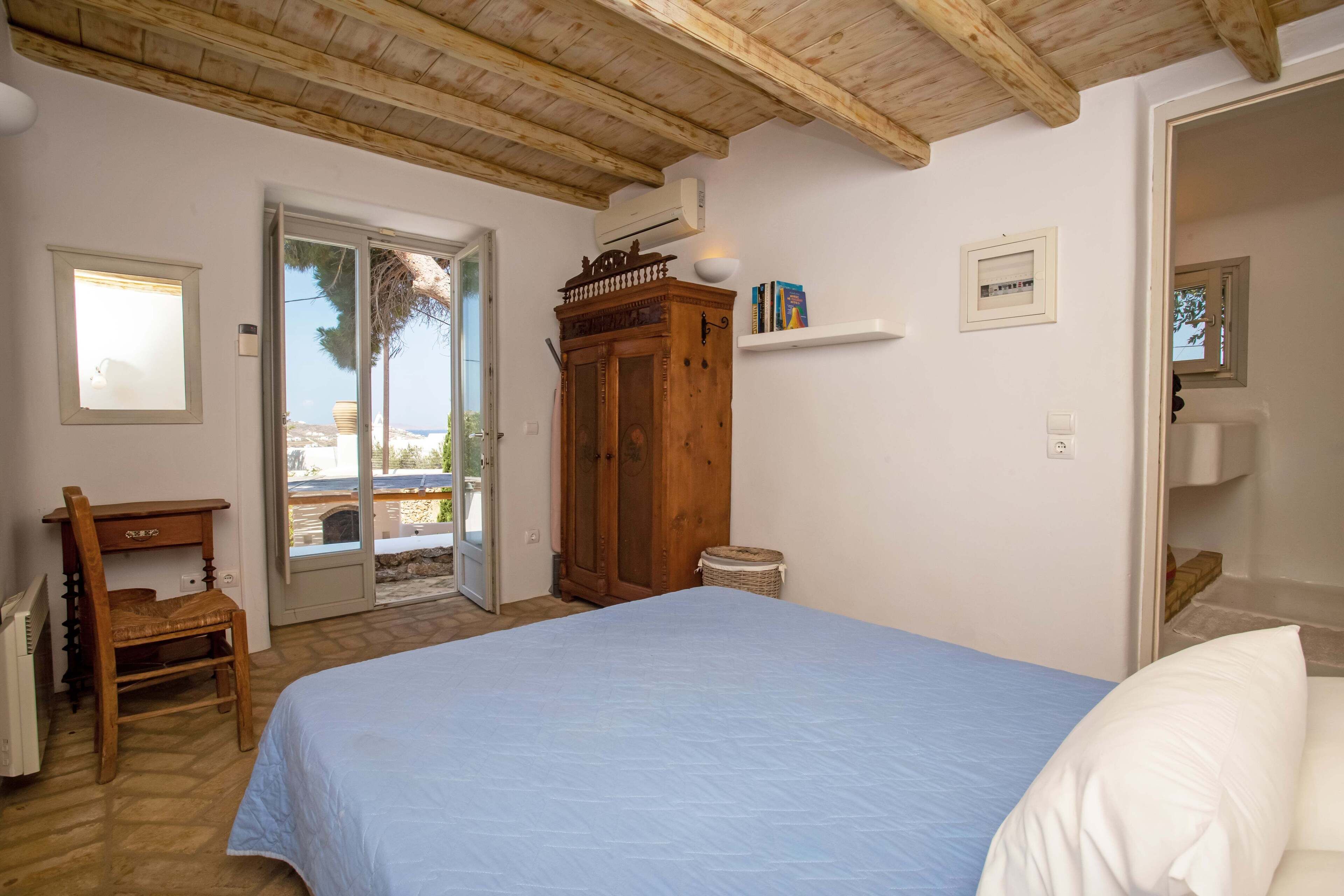 A bedroom with a bed, wooden desk, and a wardrobe.