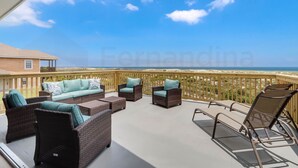 Un balcon doté de meubles en osier et offrant une vue sur la plage.
