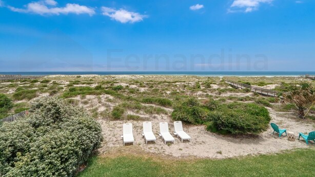 Une plage avec des chaises longues blanches et une promenade en bois.