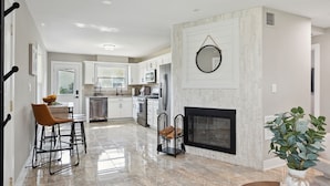 A modern kitchen with white cabinets, a built-in oven, and a dining area with bar stools. - Charming Contemporary Family Home 3 Bedroom Home by RedAwning (Glenview)