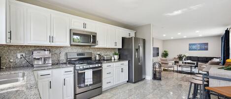 A modern kitchen with white cabinets, stainless steel appliances, and a tiled backsplash.