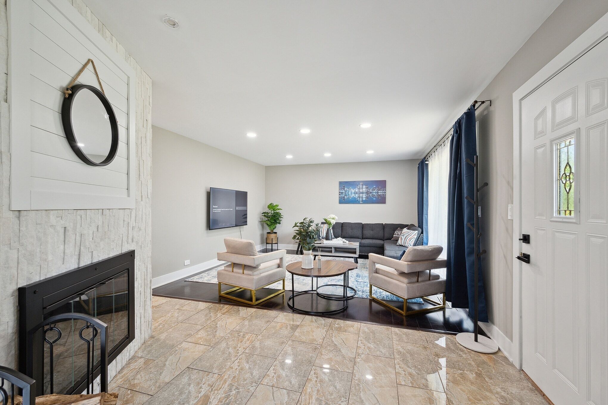 Una sala de estar moderna con chimenea, dos sillones, una mesa de centro y un sofá.