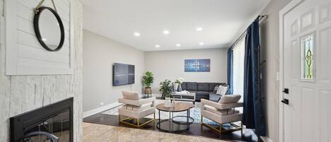 Una sala de estar moderna con chimenea, dos sillones, una mesa de centro y un sofá.